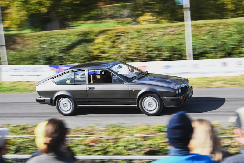 Dark grey Alfa Romeo GTV racing on a circuit, showing the coupe's sporting character